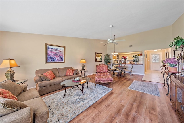 living room with light hardwood / wood-style floors, vaulted ceiling, and ceiling fan