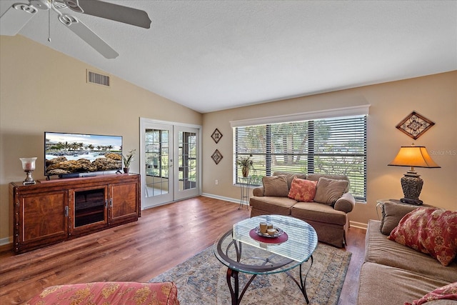 living room with a textured ceiling, french doors, lofted ceiling, and light wood-type flooring