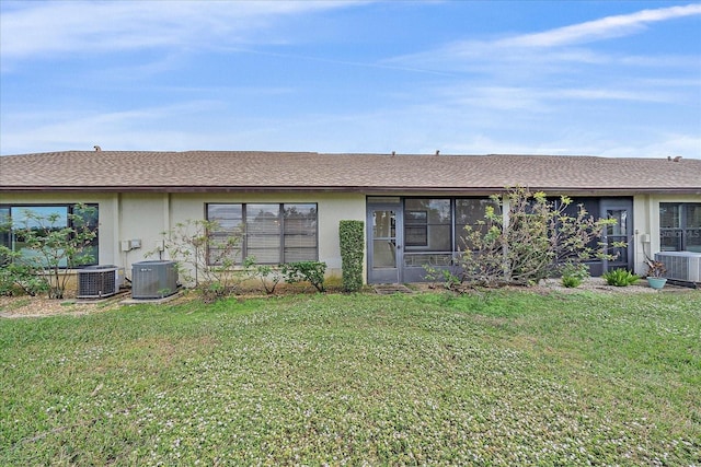 rear view of property featuring a lawn and central air condition unit