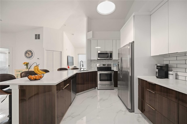 kitchen featuring white cabinets, decorative backsplash, stainless steel appliances, and sink