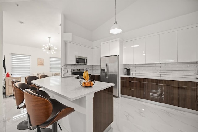 kitchen featuring white cabinetry, tasteful backsplash, vaulted ceiling, decorative light fixtures, and appliances with stainless steel finishes