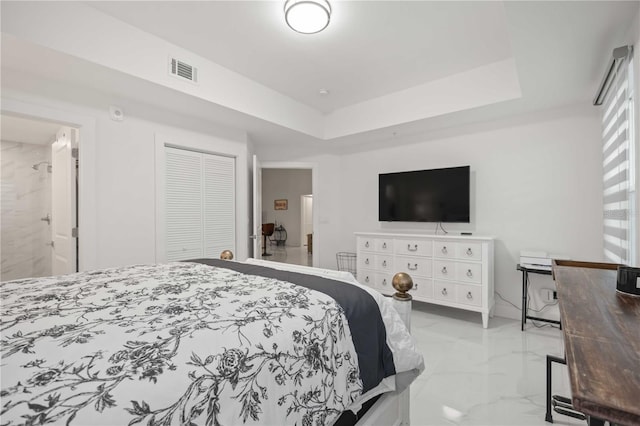 bedroom featuring connected bathroom, a tray ceiling, and a closet