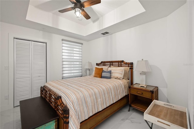 bedroom featuring ceiling fan, a raised ceiling, and a closet