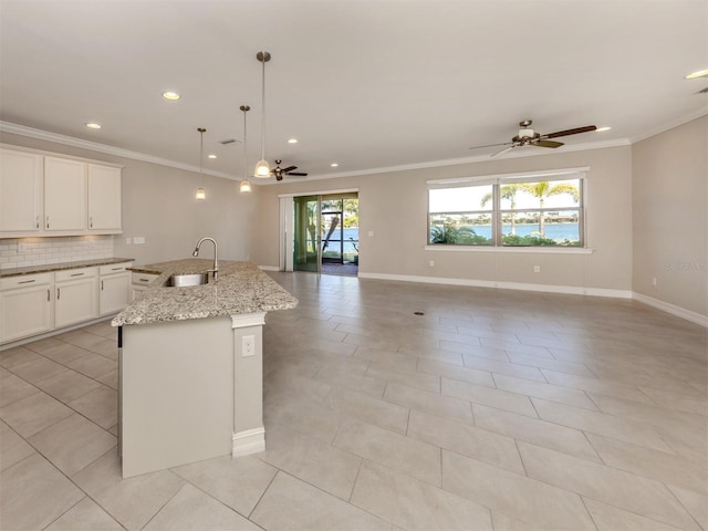 kitchen with pendant lighting, a kitchen island with sink, plenty of natural light, and sink