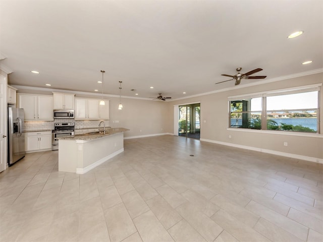 kitchen featuring white cabinetry, light stone countertops, hanging light fixtures, an island with sink, and appliances with stainless steel finishes