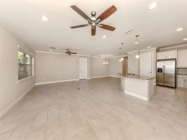 unfurnished living room featuring ceiling fan with notable chandelier, ornamental molding, sink, and light tile patterned floors