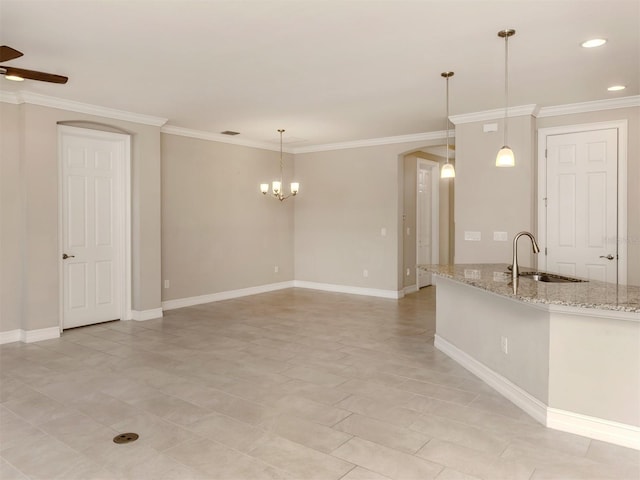 kitchen featuring light stone counters, sink, ceiling fan with notable chandelier, and decorative light fixtures