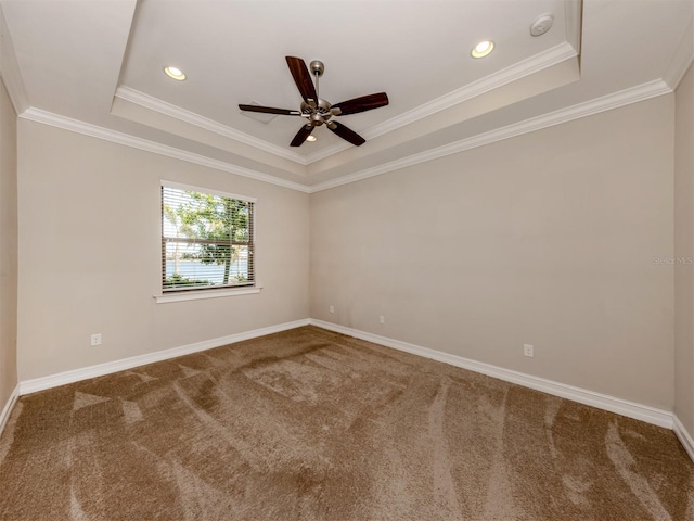 carpeted empty room featuring a tray ceiling, ceiling fan, and ornamental molding