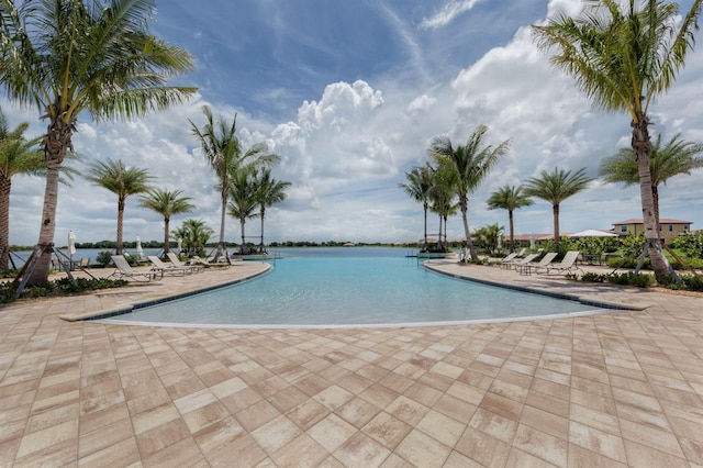 view of pool featuring a water view and a patio