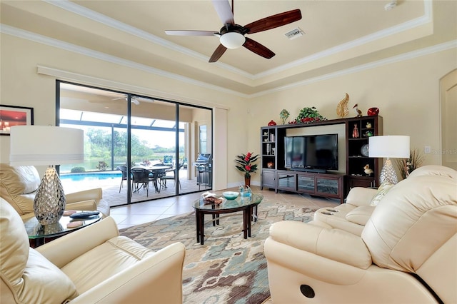 living room with ceiling fan, light tile patterned flooring, crown molding, and a tray ceiling