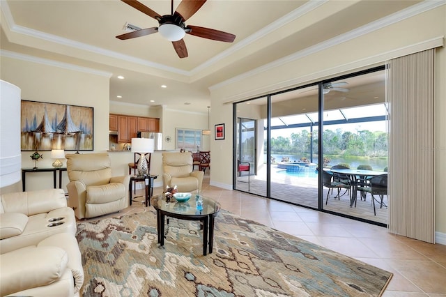 living room with ceiling fan, light tile patterned floors, ornamental molding, and a tray ceiling