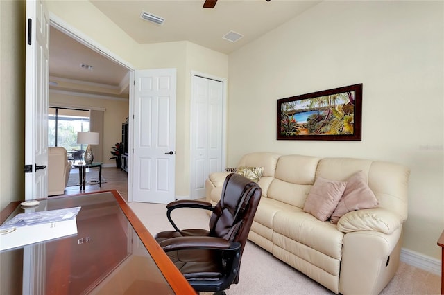 carpeted office space featuring ceiling fan and a tray ceiling