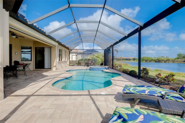 view of swimming pool with glass enclosure, a patio area, a water view, and an in ground hot tub