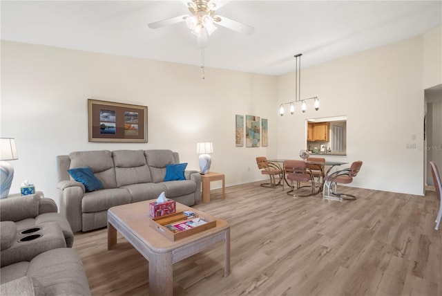 living room featuring a towering ceiling, light hardwood / wood-style floors, and ceiling fan