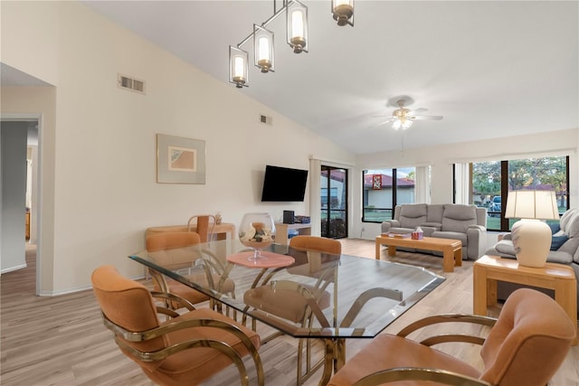 dining space featuring ceiling fan with notable chandelier, light wood-type flooring, and high vaulted ceiling