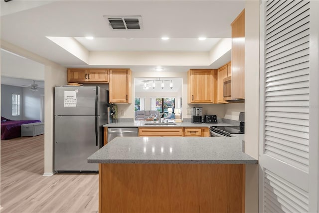 kitchen featuring kitchen peninsula, appliances with stainless steel finishes, light wood-type flooring, and light stone counters