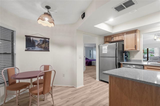 kitchen featuring decorative light fixtures, light wood-type flooring, appliances with stainless steel finishes, and dark stone counters