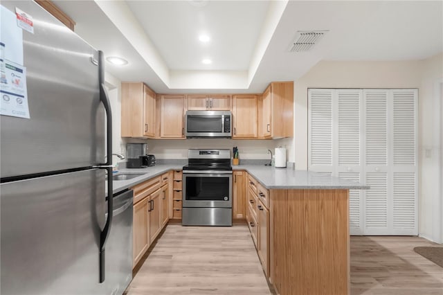 kitchen with sink, kitchen peninsula, light brown cabinetry, appliances with stainless steel finishes, and light wood-type flooring