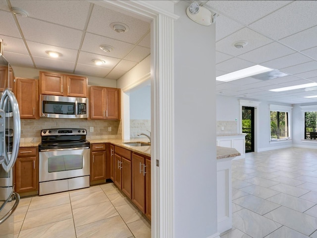 kitchen with sink, a drop ceiling, stainless steel appliances, backsplash, and light tile patterned floors