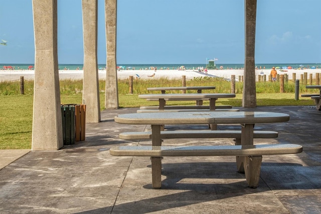 view of home's community with a yard, a water view, and a view of the beach