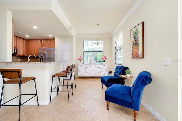 kitchen with a kitchen bar, appliances with stainless steel finishes, crown molding, pendant lighting, and a chandelier