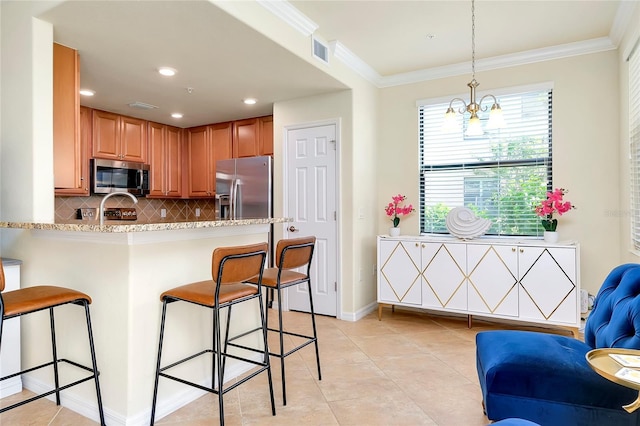 kitchen with stainless steel appliances, an inviting chandelier, kitchen peninsula, pendant lighting, and a breakfast bar area