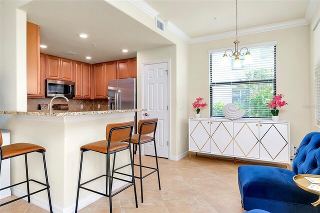 20100 Ragazza Cir Unit 101, Venice, FL 34293 - kitchen featuring stainless steel appliances, a kitchen bar, decorative backsplash, light tile patterned floors, and a peninsula
