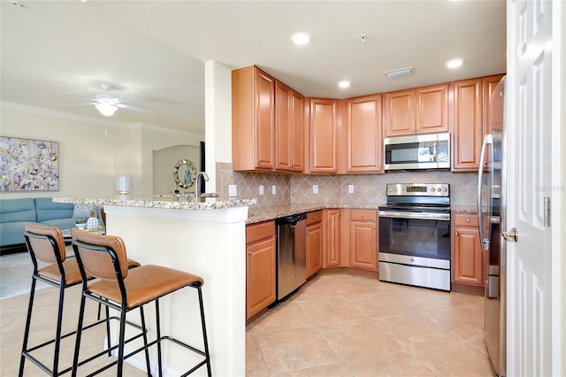 20100 Ragazza Cir Unit 101, Venice, FL 34293 - kitchen featuring stainless steel appliances, open floor plan, ceiling fan, a kitchen breakfast bar, and decorative backsplash