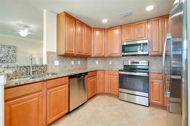 20100 Ragazza Cir Unit 101, Venice, FL 34293 - kitchen featuring stainless steel appliances, light stone counters, a ceiling fan, backsplash, and crown molding