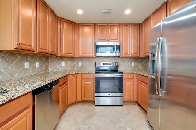 kitchen featuring light stone countertops, light tile patterned floors, stainless steel appliances, and tasteful backsplash