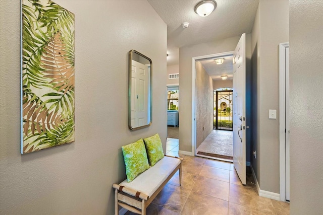 hallway featuring a textured ceiling and light tile patterned floors