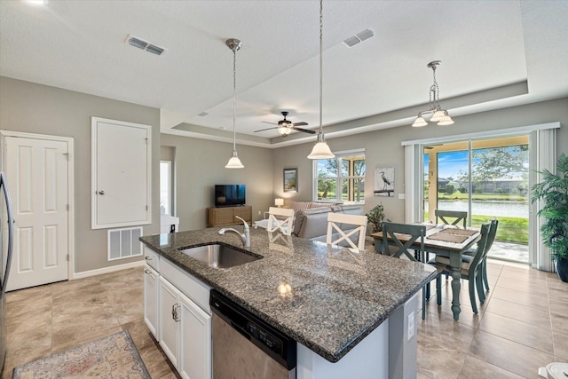 kitchen featuring white cabinetry, a tray ceiling, a kitchen island with sink, dishwasher, and sink