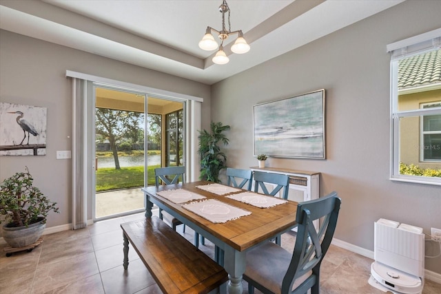 tiled dining space featuring a wealth of natural light, a raised ceiling, and a chandelier