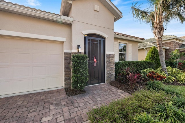 2049 Mesic Hammock Way, Venice, FL 34292 - view of exterior entry featuring stone siding, stucco siding, an attached garage, and a tiled roof