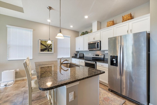 2049 Mesic Hammock Way, Venice, FL 34292 - kitchen with stainless steel appliances, white cabinets, a center island with sink, dark stone counters, and pendant lighting