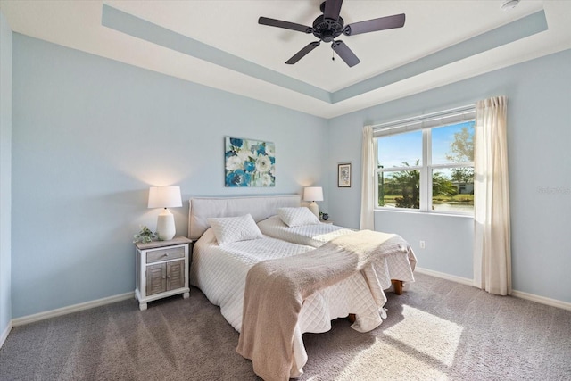 carpeted bedroom featuring ceiling fan and a tray ceiling