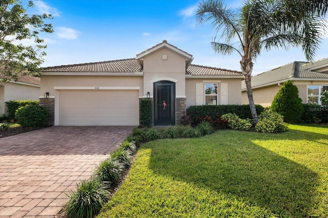 2049 Mesic Hammock Way, Venice, FL 34292 - mediterranean / spanish-style home with stone siding, decorative driveway, an attached garage, stucco siding, and a front lawn
