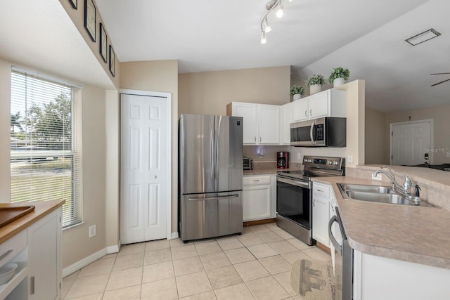 kitchen with sink, white cabinets, vaulted ceiling, and appliances with stainless steel finishes