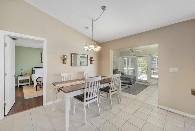 dining room with ceiling fan with notable chandelier, light hardwood / wood-style floors, and vaulted ceiling