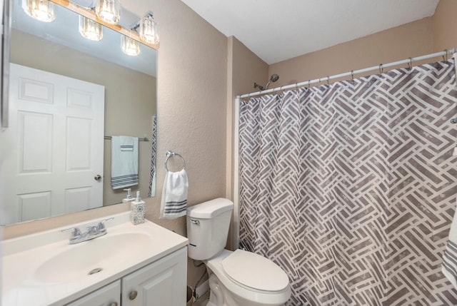 bathroom featuring toilet, vanity, and walk in shower