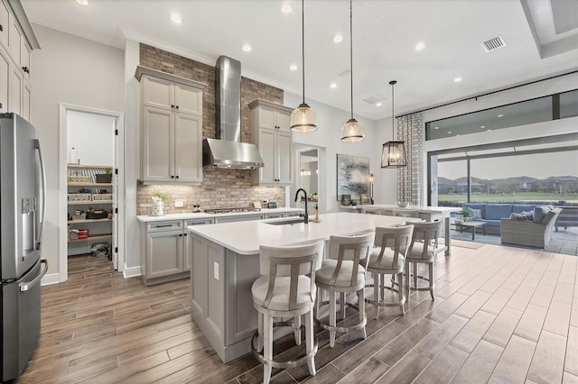 kitchen featuring gray cabinetry, sink, wall chimney exhaust hood, hanging light fixtures, and appliances with stainless steel finishes