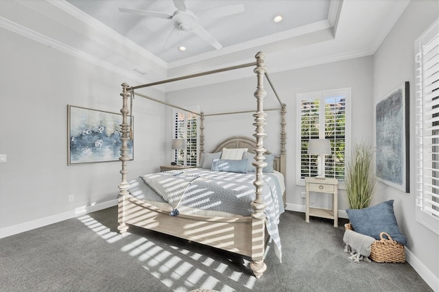 bedroom featuring dark colored carpet, ceiling fan, ornamental molding, and a tray ceiling