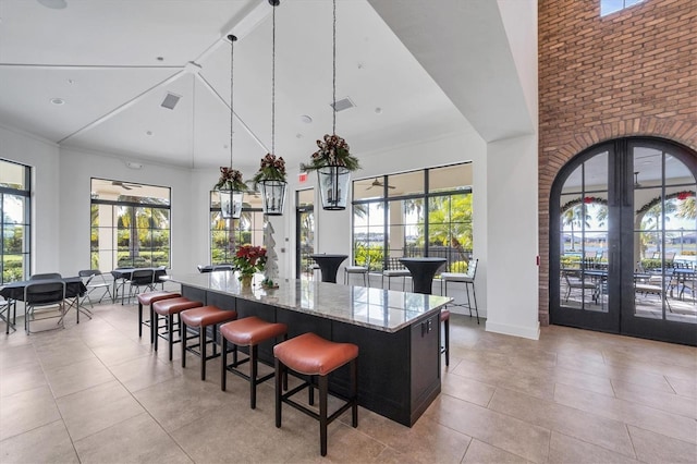 kitchen with decorative light fixtures, a kitchen island, light stone countertops, and a wealth of natural light