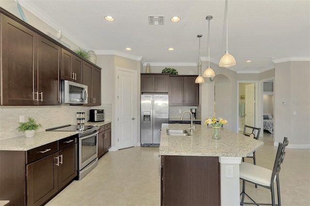 kitchen featuring a center island with sink, hanging light fixtures, crown molding, sink, and appliances with stainless steel finishes