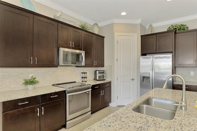 kitchen with light stone counters, dark brown cabinetry, stainless steel appliances, crown molding, and sink