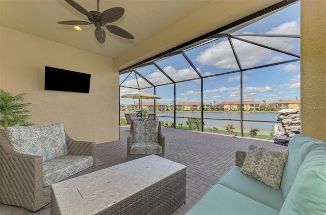 view of patio / terrace featuring glass enclosure, ceiling fan, a water view, and an outdoor hangout area