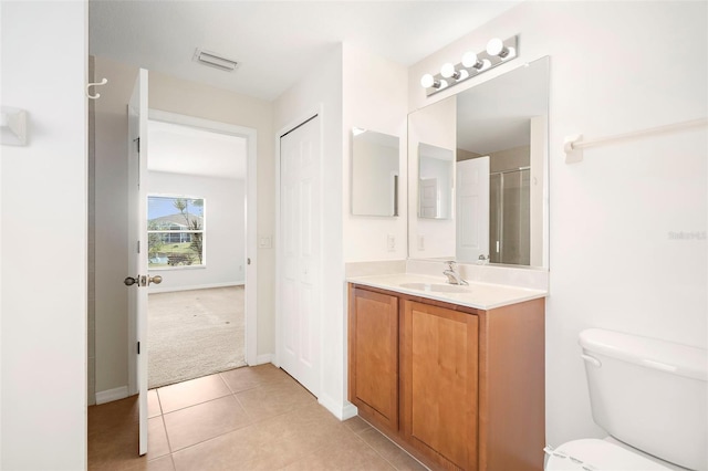 bathroom with tile patterned floors, vanity, toilet, and a shower with door