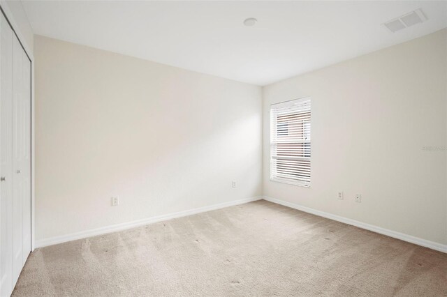 unfurnished bedroom with light carpet and a closet