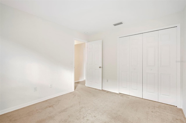 unfurnished bedroom with light carpet and a closet