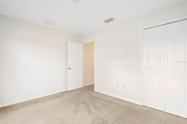 unfurnished bedroom featuring light colored carpet and a closet